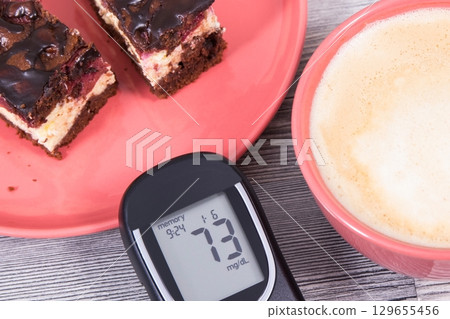 Glucose meter with result of sugar level, cheesecake with cherries and chocolate Glucose meter with result of sugar level, cheesecake with cherries and chocolate 129655456
