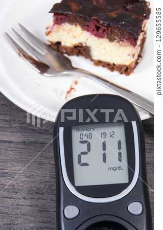 Glucometer with high result of sugar level and fresh cheesecake with cherries and chocolate Glucometer with high result of sugar level and fresh cheesecake with cherries and chocolate 129655585
