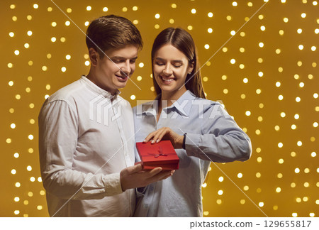 Couple in love with red box on yellow background with bright bulbs, close-up 129655817