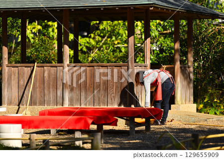 A woman sweeping fallen leaves from a teahouse A woman sweeping fallen leaves from a teahouse 129655909