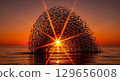 A stunning photograph of a 'solar flare' bursting from the ocean's surface at sunset, created by a massive school of fish moving in unison. 129656008