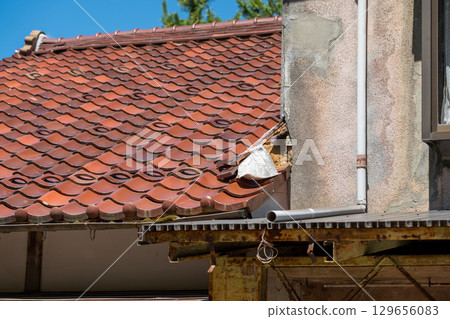 Damaged roof of an old private house 129656083