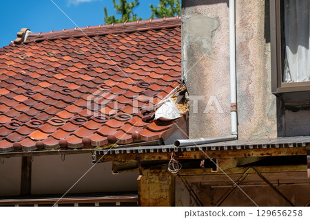Damaged roof of an old private house Damaged roof of an old private house 129656258
