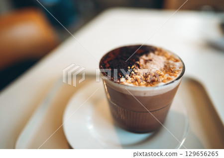 cocoa cup with nuts coconut flakes in cafe, warm indulgence and cozy delight, chocolate beverage topped with chopped nuts shredded coconut in coffee shop cocoa cup with nuts coconut flakes in cafe, warm indulgence and cozy delight, chocolate beverage topped with chopped nuts shredded coconut in coffee shop 129656265