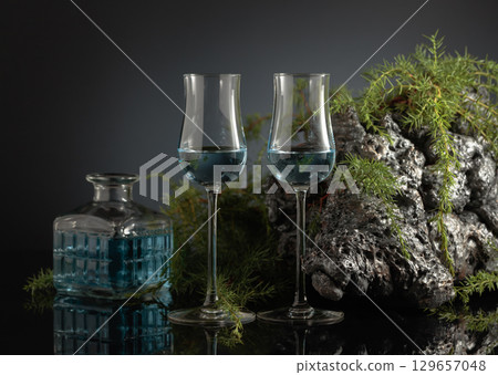 Blue gin on a black reflective background. 129657048