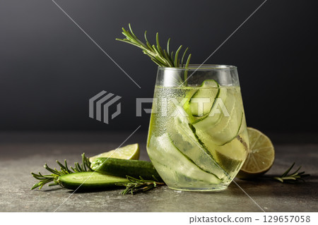 Hard seltzer with ice, rosemary, lime, and cucumber on a stone table. 129657058
