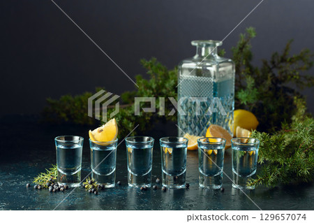 Gin with juniper berries and lemon slices. Gin with juniper berries and lemon slices. 129657074