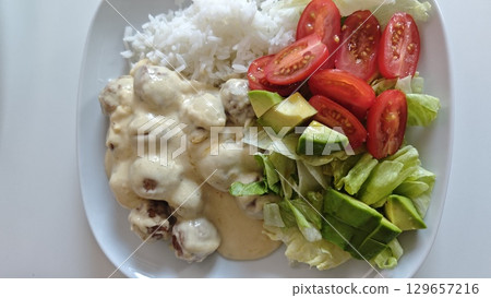 Meatballs in creamy sauce served with white rice, lettuce, avocado, and cherry tomatoes Meatballs in creamy sauce served with white rice, lettuce, avocado, and cherry tomatoes 129657216