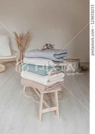 Stack of folded bedding in pastel colors on wooden bench in cozy room Stack of folded bedding in pastel colors on wooden bench in cozy room 129658255