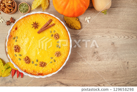 Homemade pumpkin pie decorated with walnuts, seeds, and spices for Thanksgiving celebration. top view. copy space 129658298