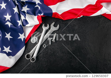 Wrenches and bolts with American flag on black background symbolizing U.S. Labor Day. top view. copy space 129658307