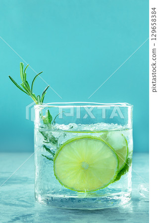 Gin tonic glass, side view with rosemary and lime. Fresh summer cocktail 129658384