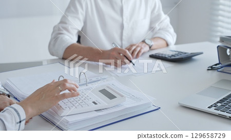 Close up of a calculator on financial documents, with an accountant hands working with, finance, and tax preparation. Audit and taxes in business 129658729