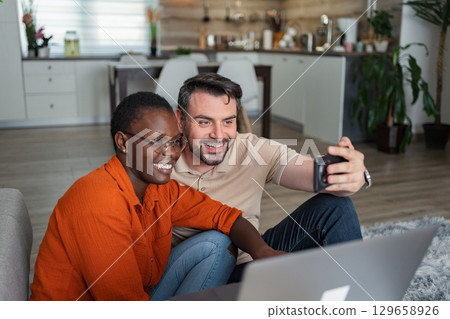 Happy couple taking a selfie at home using a smartphone 129658926