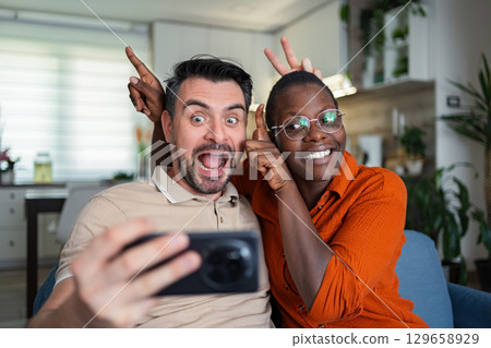 Playful couple taking a selfie making funny faces at home 129658929