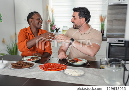 Interracial Couple Toasting with Water During Lunch at Home 129658933