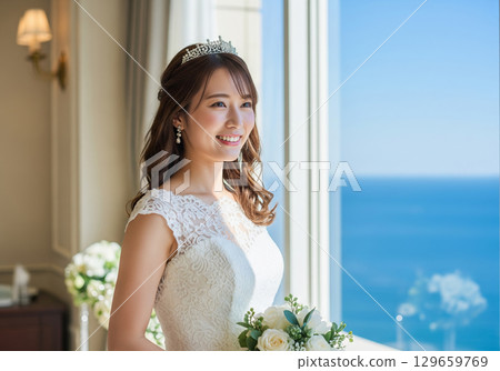 身穿婚紗、頭戴皇冠的女子在飯店裡眺望大海 129659769