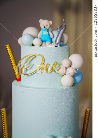 a blue three-tiered cake decorated with bear cub and caramel balls a blue three-tiered cake decorated with bear cub and caramel balls 129659837
