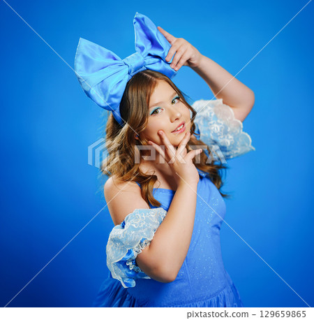 Cute teenage girl in blue doll dress with big blue bow posing. Cute teenage girl in blue doll dress with big blue bow posing. 129659865