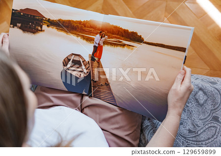 woman is holding and flipping through a photo book with a pregnancy photo shoot woman is holding and flipping through a photo book with a pregnancy photo shoot 129659899