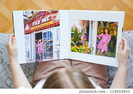 woman is holding and flipping through a photo book with a pregnancy photo shoot 129659943