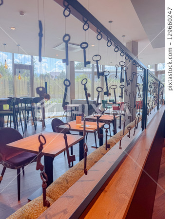 Unique restaurant interior featuring rows of vintage keys as decorative partition. Warm light, wooden textures and creative atmosphere. Perfect for editorial use and design inspiration. Unique restaurant interior featuring rows of vintage keys as decorative partition. Warm light, wooden textures and creative atmosphere. Perfect for editorial use and design inspiration. 129660247