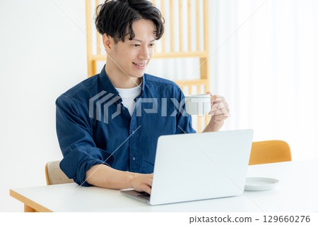 年輕人一邊喝咖啡一邊操作電腦 129660276