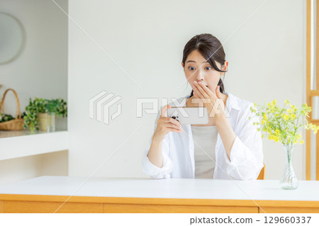 一個女人驚訝地看到一部智能手機 129660337