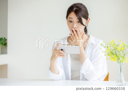 一個女人驚訝地看到一部智能手機 一個女人驚訝地看到一部智能手機 129660338