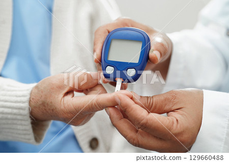 Doctor check diabetes from finger blood sugar level with digital glucose monitor measure and test stripe. 129660488