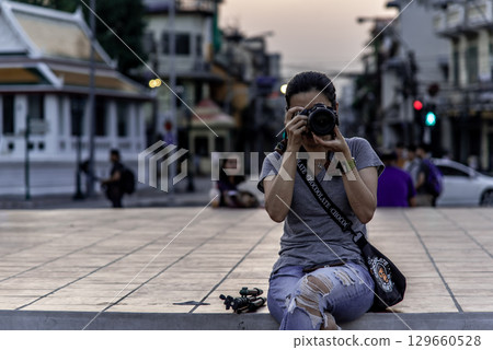 A Woman siting down on the floor and takes pictures with a camera at The Giant Swing (Sao Ching Cha). A Woman siting down on the floor and takes pictures with a camera at The Giant Swing (Sao Ching Cha). 129660528