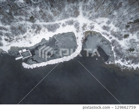 November landscape with covered with first snow birch and spruce forest on lake shore. First snow on lake. 129662759