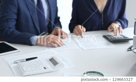Calculator and magnifying glass over financial documents opposite financial team analyzing data, reviewing reports, collaborating at modern office workspace, close up view. Audit and taxes Calculator and magnifying glass over financial documents opposite financial team analyzing data, reviewing reports, collaborating at modern office workspace, close up view. Audit and taxes 129663327