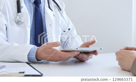 Close-up of doctor man showing information on tablet to patient woman during medical visit, explaining diagnosis and treatment options, providing medical consultation. Medicine concept Close-up of doctor man showing information on tablet to patient woman during medical visit, explaining diagnosis and treatment options, providing medical consultation. Medicine concept 129663371