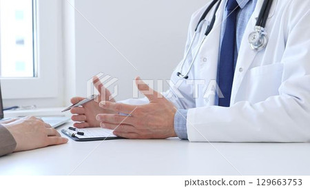Adult doctor gesturing with hands while explaining diagnosis to patient during medical consultation in hospital office, healthcare and medical concept. Medicine concept 129663753