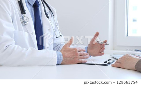 Adult doctor gesturing with hands while explaining diagnosis to patient during medical consultation in hospital office, healthcare and medical concept. Medicine concept 129663754