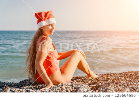 Woman in Red Swimsuit and Santa Hat on a Beach 129664686
