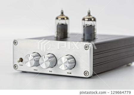 Silver audio amplifier with vacuum tubes metal front panel three control knobs modern design isolated on white background high fidelity retro style clean shiny elegant Silver audio amplifier with vacuum tubes metal front panel three control knobs modern design isolated on white background high fidelity retro style clean shiny elegant 129664779