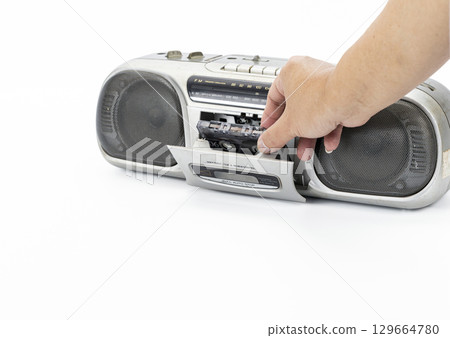 Hand inserting cassette into vintage portable stereo player, retro audio equipment, nostalgic mood, isolated on white background, close up, music lover, technology concept 129664780