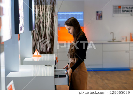 A female designer in a furniture store choosing wooden drawer in furniture store. A female designer in a furniture store choosing wooden drawer in furniture store. 129665059