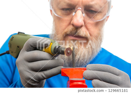 Craftsman performing detailed work with rotary tool on metal in workshop 129665181
