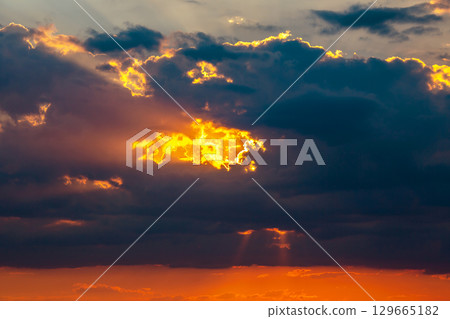 Dramatic sunset sky with orange and gold hues over a moody landscape 129665182