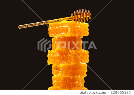Delicious honeycomb stacked with a honey dipper resting on top 129665185