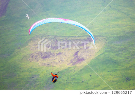 Paragliding adventure over the lush landscapes of Iceland's scenic hills 129665217