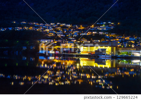 Night view of a picturesque village in Norway with lights reflecting on the water Night view of a picturesque village in Norway with lights reflecting on the water 129665224