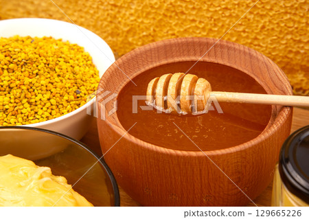 Honey and bee pollen in wooden bowl with wax and comb on wooden surface Honey and bee pollen in wooden bowl with wax and comb on wooden surface 129665226
