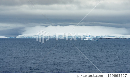 Ice Edge along Antarctic Coastline under Cloudy Sky 129665527
