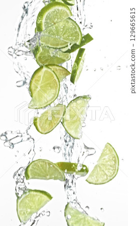 Fresh Lime Slices Falling in Water Splashes, isolated on White Background. Freeze Motion of Fruit Beverages. Fresh Lime Slices Falling in Water Splashes, isolated on White Background. Freeze Motion of Fruit Beverages. 129665615
