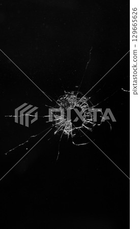 Bullet Destruction. Dirty Glass Broken into a Large Number of Pieces and Parts, a Piece of Glass with a lot of Cracks and Broken Parts. Isolated on Black Background. 129665626