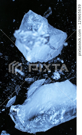 Broken Ice. Crushed Textured Ice with Cracks on a Black Background, Close-up. Abstract Background with Crushed Ice Pieces. Vertical Aspect Ratio. 129665639